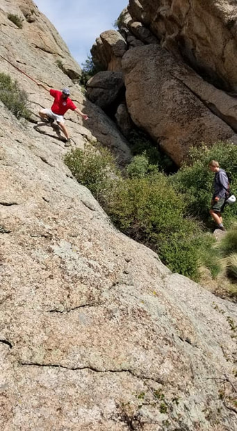Marty Fahncke helping a boy scout up a cliff